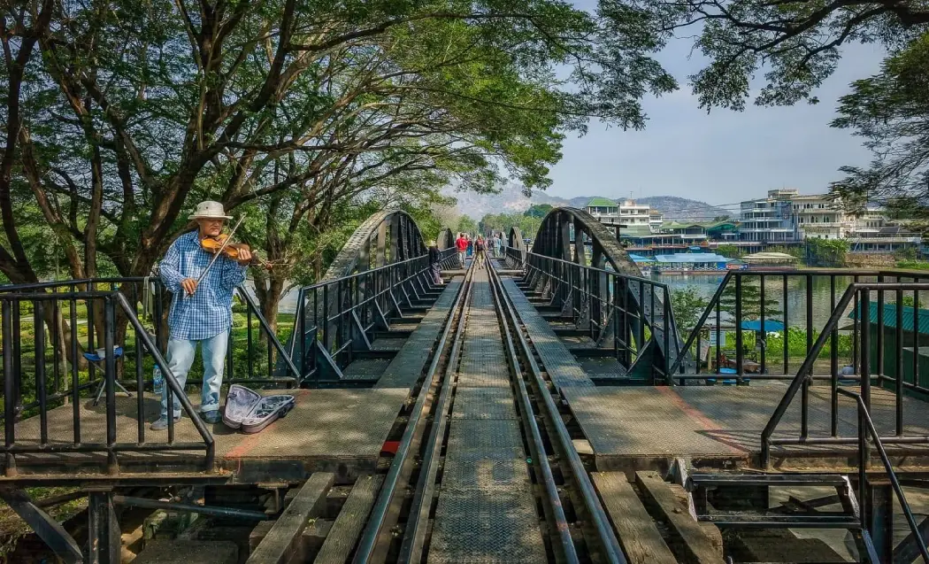 A musician playing violin on the bridge and tourists enjoying their trip