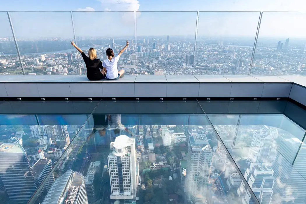 Two friends sitting on the Glass Tray in the Mahanakhon Skywalk