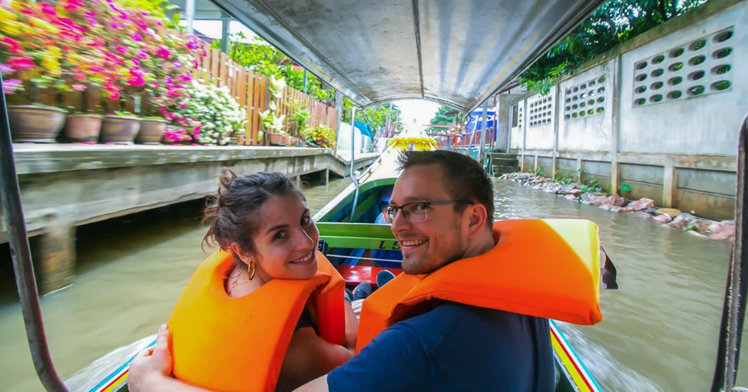 A couple enjoying a long-tail boat ride through a canal near Bangkok.
