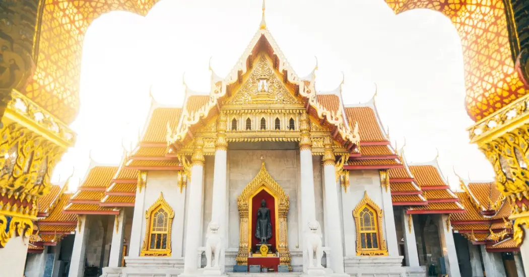 Sunlit view of the Marble Temple with golden roofs and white pillars