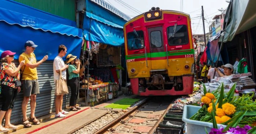Tourists taking photos of train arrival at Maeklong Railway Market