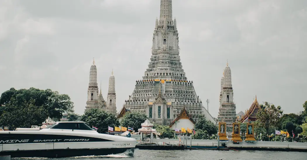 A ferry passing by Wat Arun, with the temple visible in the background