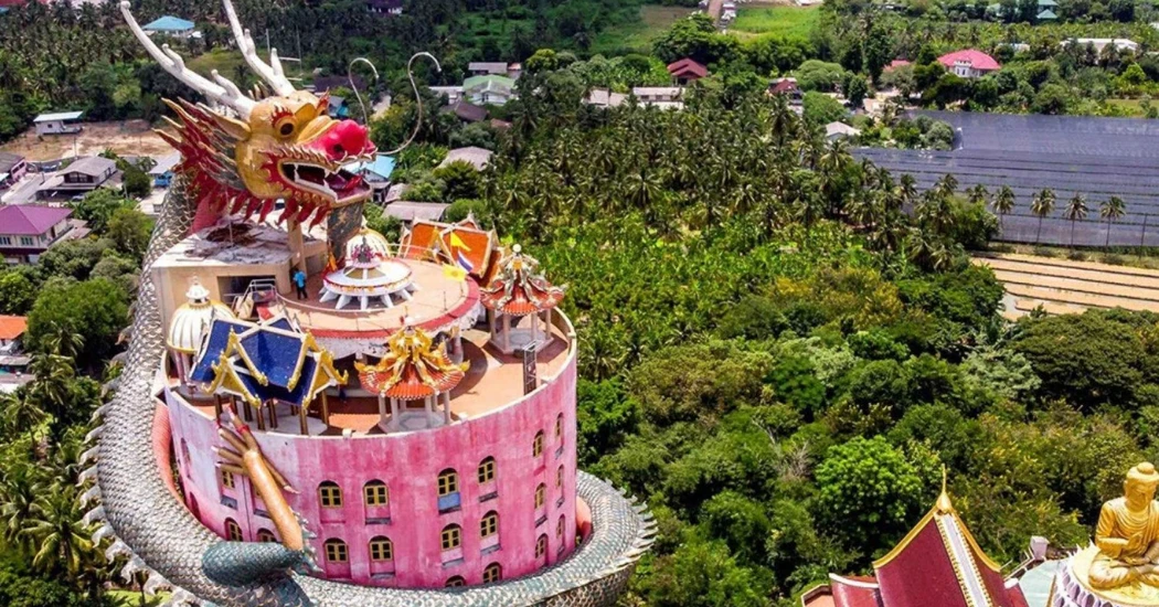 Aerial view of Wat Samphran Dragon Temple with a giant dragon wrapped around a pink tower.